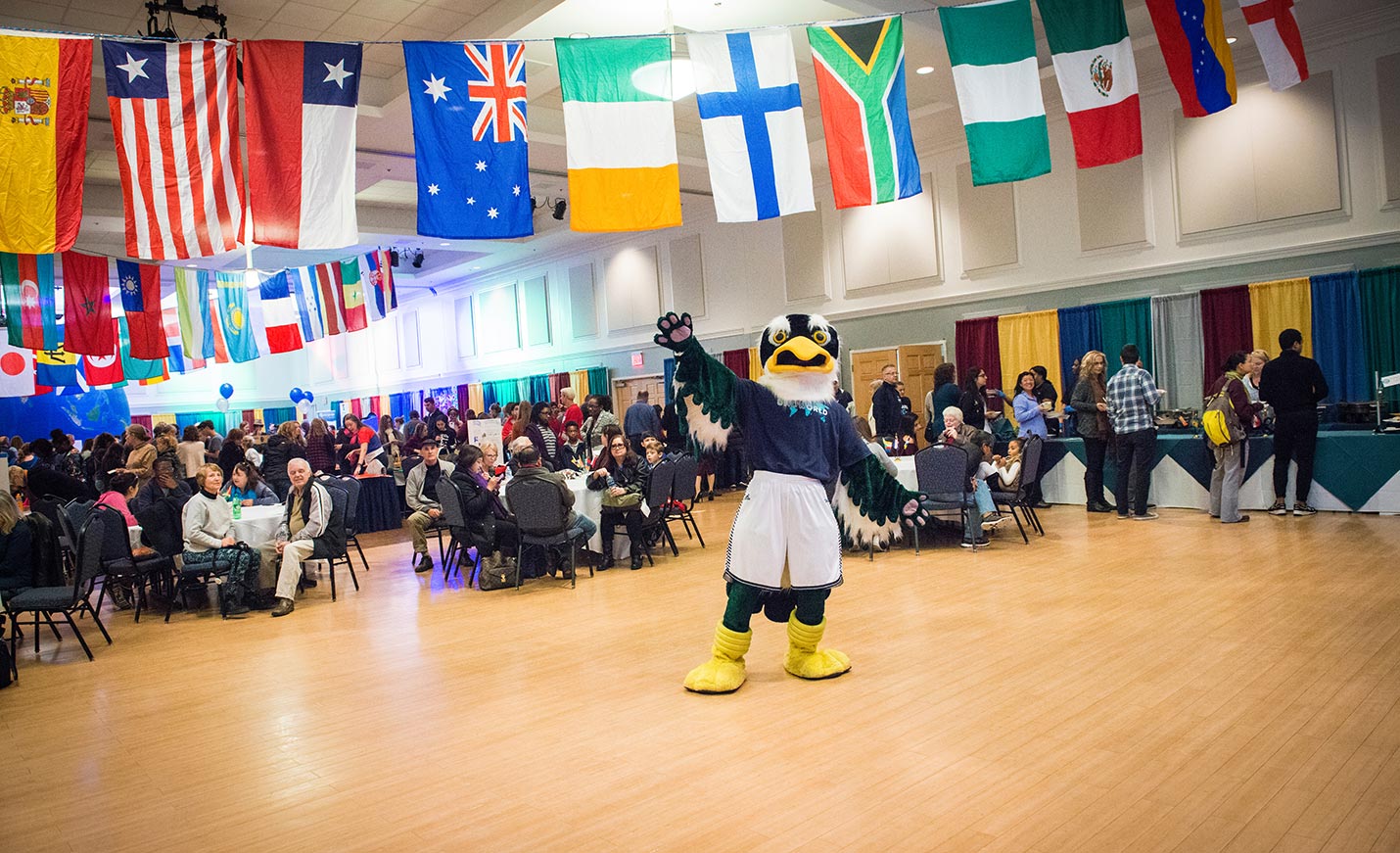 Sammy Seahawk poses amid international flags